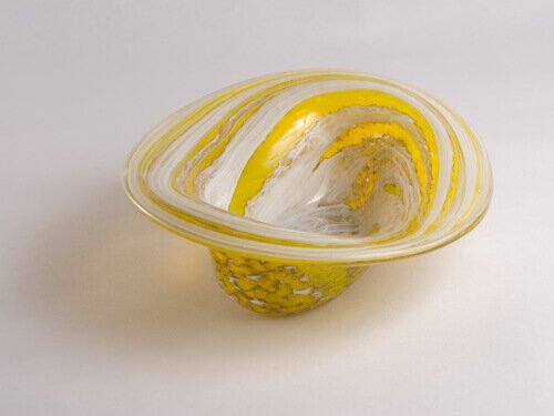 An oval, hand blown, glass vessel - yellow with white stripes