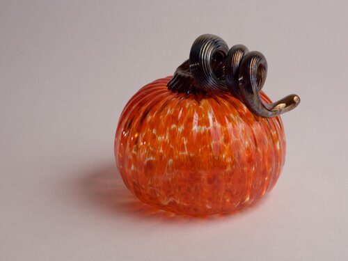 A perfectly shaped hand blown orange glass pumpkin with brown curly stem