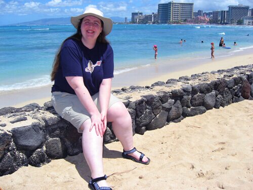 Me sitting on a rock wall with Waikiki Beach and hotels in the background